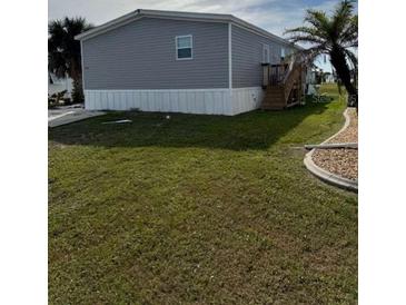 Charming home featuring gray siding, elevated design, and a well-manicured lawn at 7337 Desant Ln, Port Charlotte, FL 33981