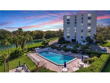 Resort-style pool and surrounding patio area with adjacent building at sunset at 220 Belleview Blvd # 609, Belleair, FL 33756