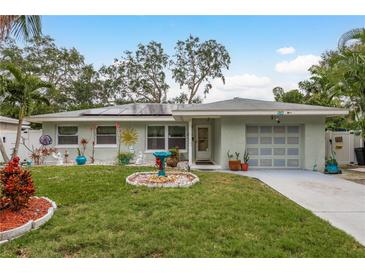 Cute bungalow with solar panels, landscaped lawn, and a two-car garage at 1611 San Charles Dr, Dunedin, FL 34698