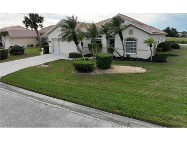 Single-story home with a landscaped lawn and palm trees at 6769 Greenview Ln, Englewood, FL 34224