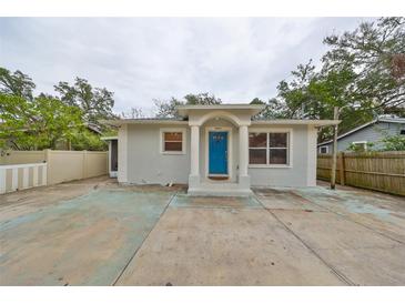 Gray house with blue door, concrete driveway, and fenced yard at 10107 N Arden Ave, Tampa, FL 33612