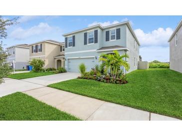 Two-story house with light blue exterior, two-car garage, and landscaped front yard at 17048 Oval Rum Dr, Wimauma, FL 33598