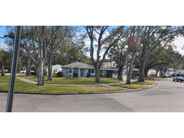 Cute bungalow home with a light blue exterior, nestled amongst mature trees at 3602 E Renellie Cir, Tampa, FL 33629