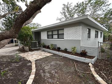 Updated home exterior with landscaped yard and paved pathway at 4108 W Oakellar Ave, Tampa, FL 33611