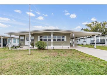 Single-wide manufactured home with carport and landscaped lawn at 5322 Comanche St, Zephyrhills, FL 33542