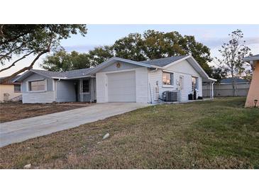 Ranch style home with a single car garage and a large grassy yard at 7930 Valmy Ln, Port Richey, FL 34668