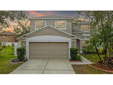 Two-story house with beige exterior, two-car garage, and landscaped yard at 10525 Lucaya Dr, Tampa, FL 33647