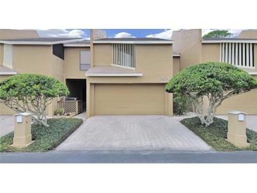 Townhouse exterior with a garage, landscaping, and a brick driveway at 13804 Mill Cove Cir, Tampa, FL 33618