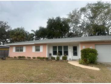 Ranch-style home with pink exterior, grey roof, and landscaped lawn at 3230 San Bernadino St, Clearwater, FL 33759