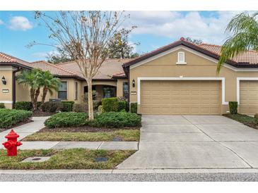 Tan two-car garage villa with a landscaped front yard at 430 Cedar Falls Dr, Apollo Beach, FL 33572