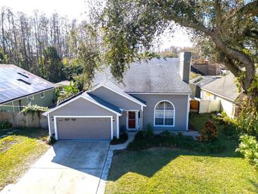 Gray house with a two-car garage, mature landscaping, and solar panels at 7120 Hideaway Trl, New Port Richey, FL 34655