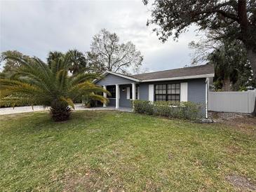 Gray house with white trim, landscaped lawn, and palm tree at 8307 Boxwood Dr, Tampa, FL 33615