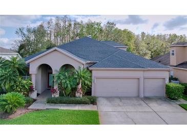 Two-story house with three-car garage and lush landscaping at 1542 Deerbourne Dr, Wesley Chapel, FL 33543