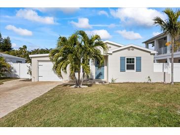 Newly renovated home with a charming facade, landscaped lawn, and paver driveway at 105 3Rd St, Belleair Beach, FL 33786