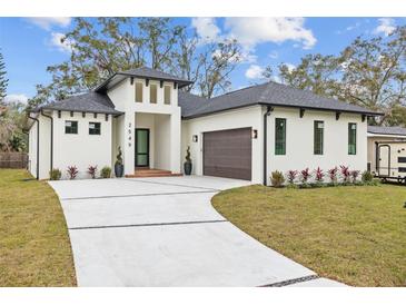Modern, single-story home with a white exterior, gray roof, and a two-car garage at 2549 Martha Ln, Land O Lakes, FL 34639