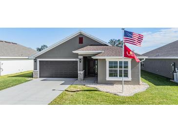 One-story home with gray siding, brown garage door, and landscaped lawn at 38189 Countryside Pl, Dade City, FL 33525