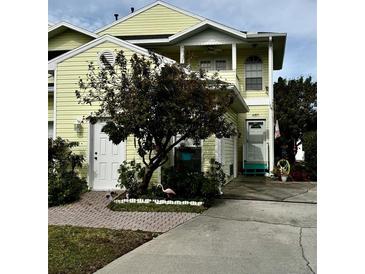 Two-story yellow house with a white garage door and landscaping at 458 Grant St, Dunedin, FL 34698