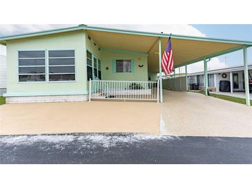 Mint green manufactured home with carport and American flag at 7050 El Matador St, Zephyrhills, FL 33541