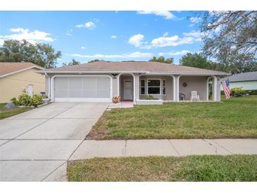 Cute ranch home with a screened-in garage and well-manicured lawn at 8130 Merrimac Dr, Port Richey, FL 34668