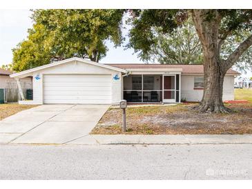 White brick ranch house with attached garage and screened porch at 9825 Lakeside Ln, Port Richey, FL 34668