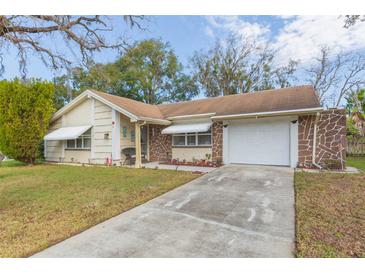 Ranch-style home with stone accents and a spacious driveway at 12512 River Mill Dr, Hudson, FL 34667