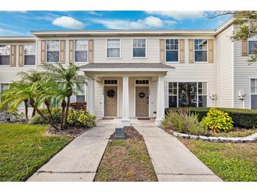 Two-story townhome with light beige siding, double door entry, and landscaping at 13630 Forest Lake Dr, Largo, FL 33771