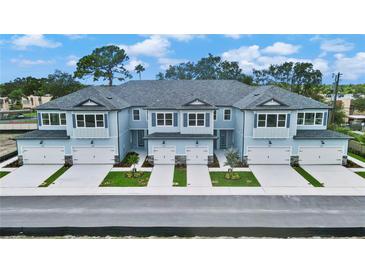 Aerial view of four townhouses with gray roofs and light blue siding, two-car garages, and landscaping at 7773 93Rd N St # 31, Seminole, FL 33777