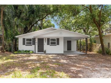 Charming bungalow with white exterior, covered carport, and well-manicured lawn at 803 E North St, Tampa, FL 33604