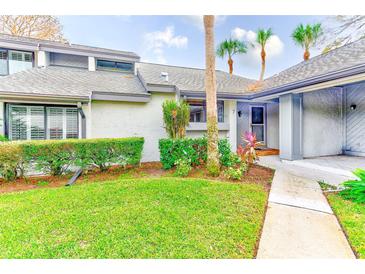 Exterior view of condo with landscaped lawn, walkway, and inviting entryway at 90 S Highland Ave # 7, Tarpon Springs, FL 34689