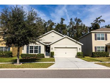 Beige house with a two-car garage and a well-maintained lawn at 10029 Warm Stone St, Thonotosassa, FL 33592