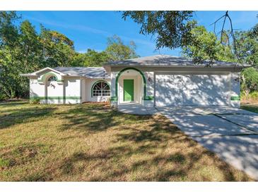 White house with green trim, attached garage, and grassy yard at 12240 Eakin St, Weeki Wachee, FL 34614