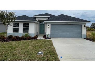 New single-story home with gray garage door and landscaping at 13299 Ogden Glade Rd, Dade City, FL 33525