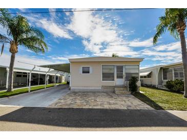 Tan single-wide manufactured home with carport and landscaped yard at 18675 Us Highway 19 N # 364, Clearwater, FL 33764