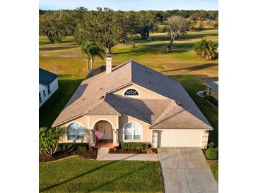 House with a tan exterior, a three-car garage, and a manicured lawn at 2102 Golf Manor Blvd, Valrico, FL 33596