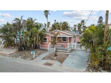 Charming pink house with a welcoming front porch, landscaping, and a paved driveway at 342 Boca Ciega Dr, Madeira Beach, FL 33708