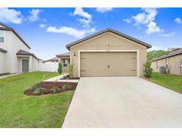 Tan house with a two-car garage and landscaped yard at 5403 Fez Ct, Brooksville, FL 34602