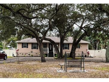 Tan house with dark shutters, front porch, and mature oak trees at 5805 34Th S Ave, Tampa, FL 33619