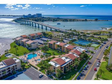 Aerial view of a waterfront community with tennis courts, pool, and lush landscaping at 845 S Gulfview Blvd # 208, Clearwater Beach, FL 33767