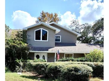 Two-story house with gray siding, large windows, and landscaped yard at 9850 Hilltop Dr, New Port Richey, FL 34654