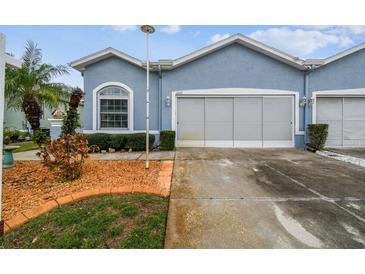 Front view of a light blue house with a two-car garage and landscaping at 11447 Golf Round Dr, New Port Richey, FL 34654