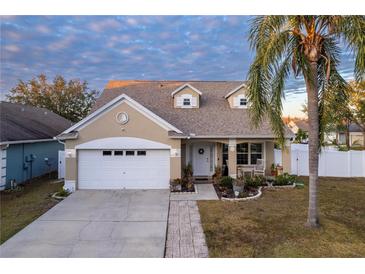 Tan house with white garage and landscaping at 17436 Lawn Orchid Loop, Land O Lakes, FL 34638