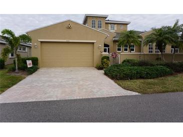 Tan two-story house with a three-car garage and landscaped yard at 2431 Kensington Greens Dr # 0, Sun City Center, FL 33573