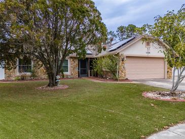 House exterior featuring stone accents, solar panels, and a well-maintained lawn at 4228 Spring Way Cir, Valrico, FL 33596