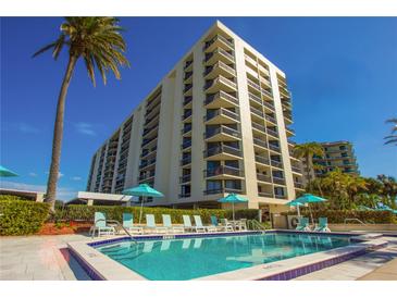 Resort-style pool and building exterior with lush landscaping at 690 Island Way # 410, Clearwater Beach, FL 33767