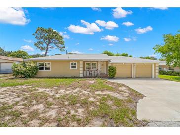 Tan single-story house with a two-car garage and mature landscaping at 1085 Indian Rocks S Rd, Largo, FL 33770