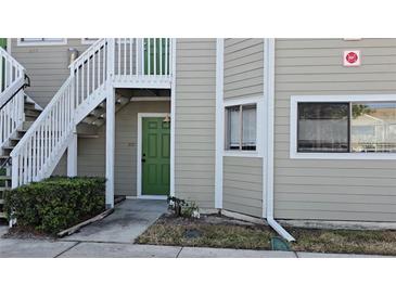 Exterior view of a light taupe condo building with green doors and stairways at 7298 Ulmerton Rd # 202, Largo, FL 33771