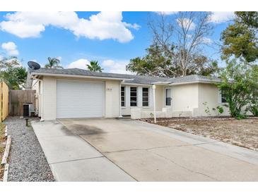 House exterior featuring a white brick facade, attached garage, and a driveway at 7810 Greybirch Ter, Port Richey, FL 34668