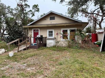 Tan single-story house with red door and small yard at 1602 Saffold Park Dr, Ruskin, FL 33570