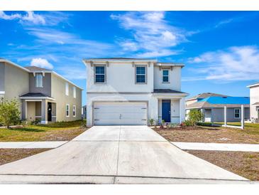 Two-story house with white exterior, two-car garage, and landscaped lawn at 17033 Oval Rum Dr, Wimauma, FL 33598