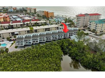 Aerial view of condo building near beach, pool, and lush landscape at 19727 Gulf Blvd # 103, Indian Shores, FL 33785